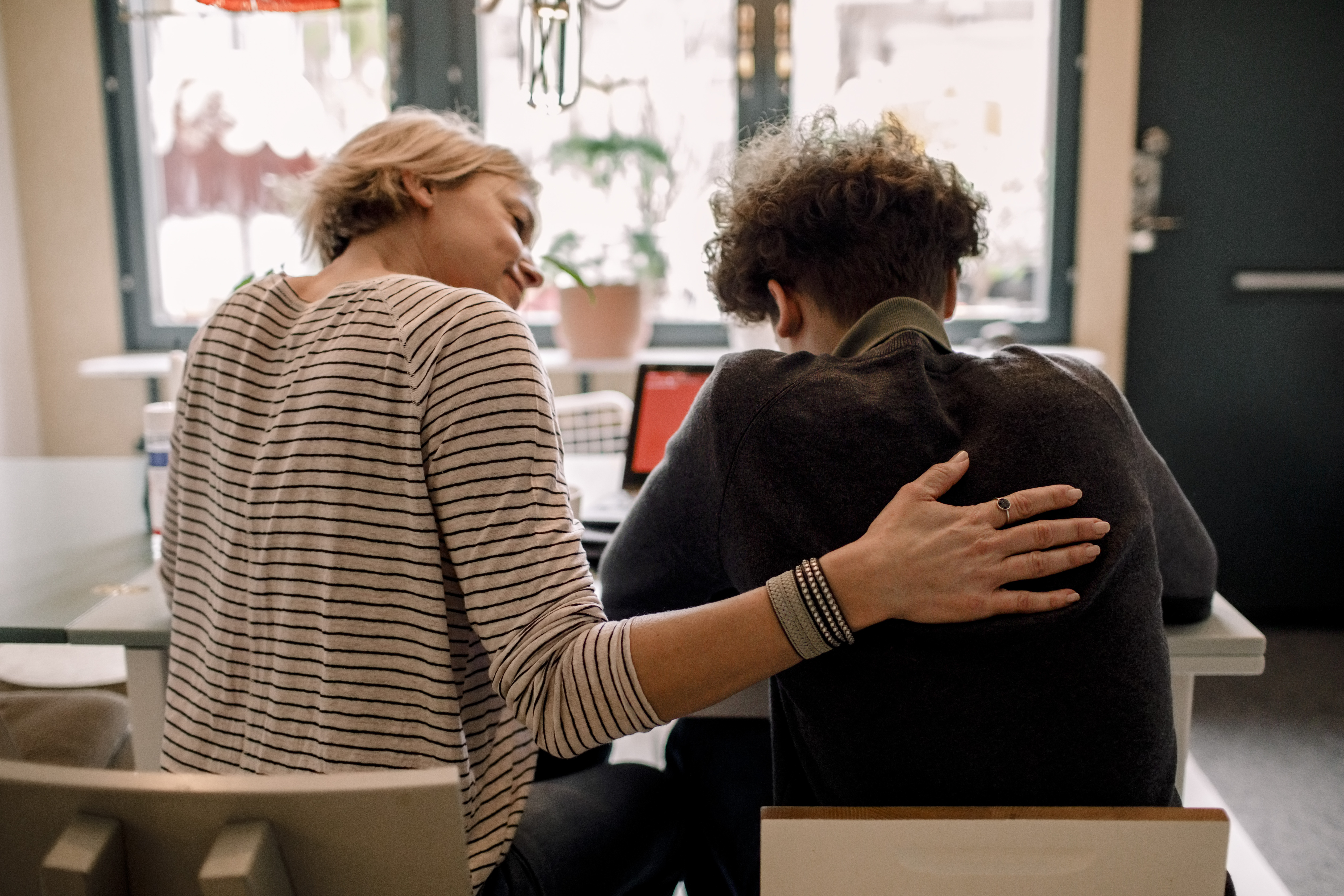 Person comforting another person with arm around back.